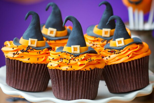 Cremefarbene Cupcakes mit Hüten auf Halloween verziert