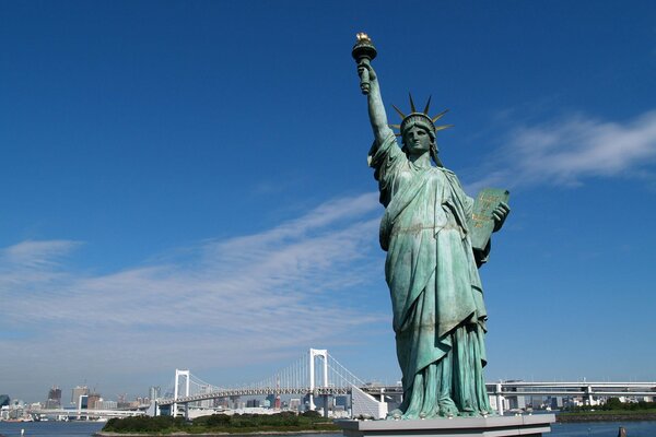 Riesige Freiheitsstatue vor dem Hintergrund einer Brücke in New York City