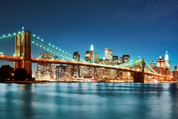 Brooklyn Bridge in der Nacht , im Hintergrund eine Stadt in Lichtern