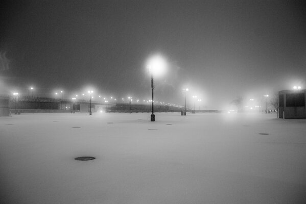 Strada notturna, urbana, deserta, innevata con lanterne luminose