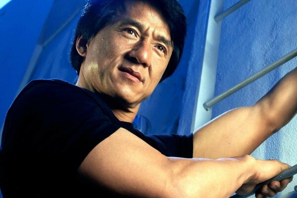 Jackie Chan holds onto the ladder with her hands