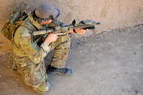 Ein Soldat in Tarnung setzt sich hin und zielt mit einem Gewehr ab