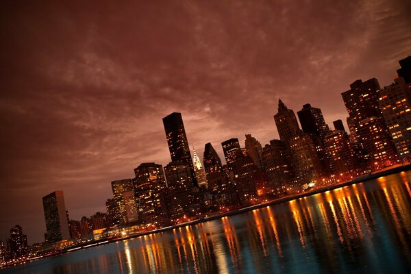 Ein Bild eines Flusses in der Nähe von New York City, der von den Lichtern der Stadt beleuchtet wird