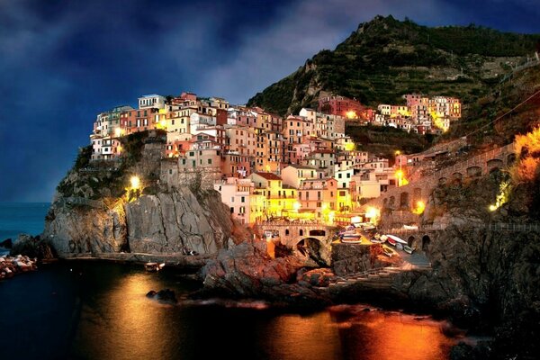 Italienische Nachtstadt auf den Felsen am Meer