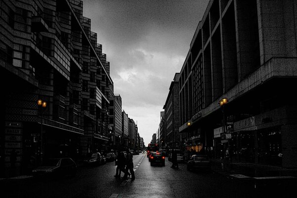 Berlín, una calle nocturna con edificios de varios pisos, autos, personas, en el fondo de un cielo nublado