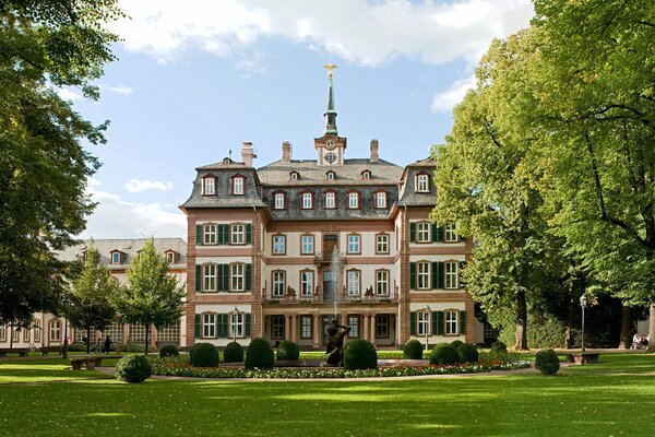 The green landscape of the park in summer . Blue sky and elegant architecture of the house