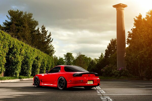 Mazda rx-7 rojo en el estacionamiento entre los árboles