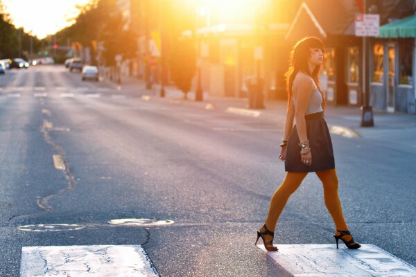 Ragazza che cammina attraverso la strada al sole della sera