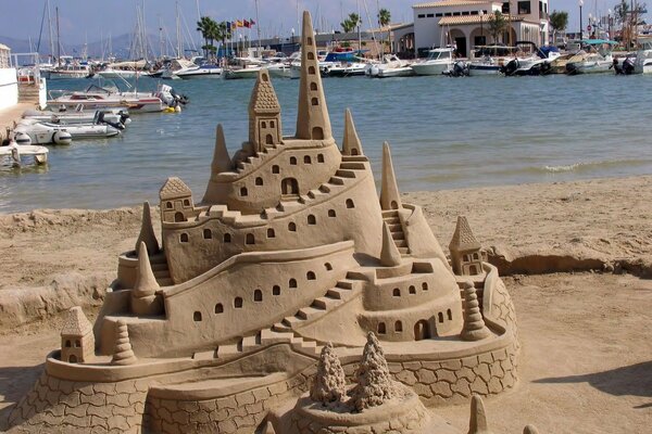 Sand castle on the background of yachts and a pond