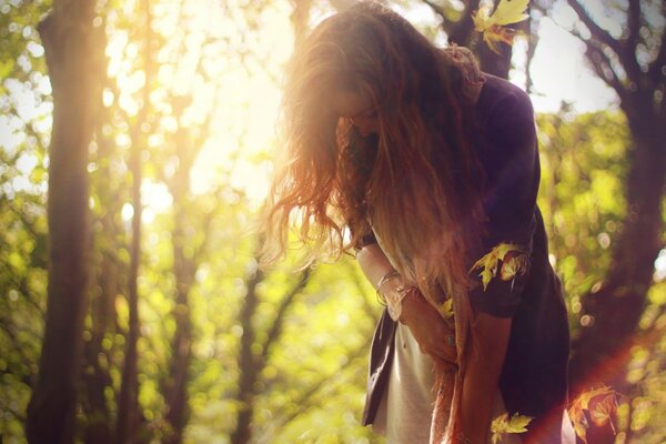 Ragazza dai capelli lunghi alla luce del sole su uno sfondo di alberi