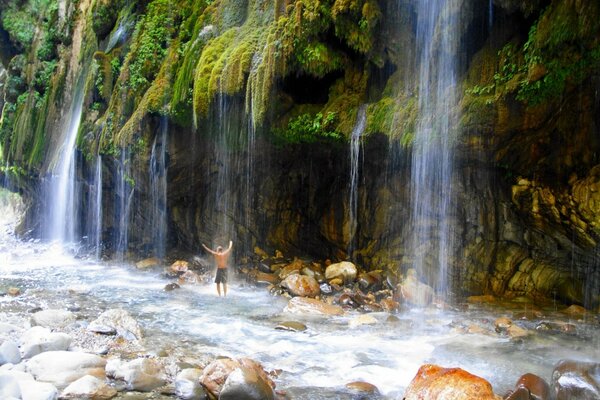 Uomo in piedi sotto una cascata in Grecia