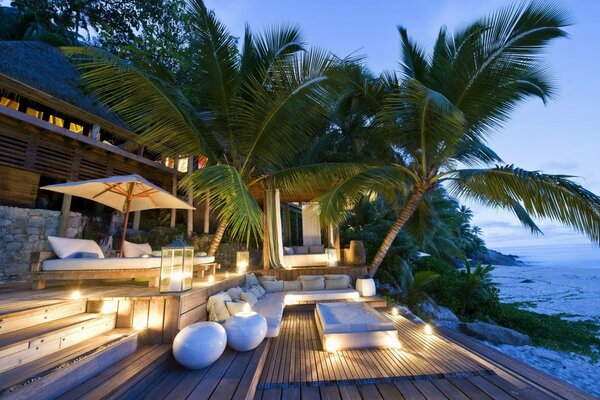 Villa en bord de mer avec palmiers dans la soirée