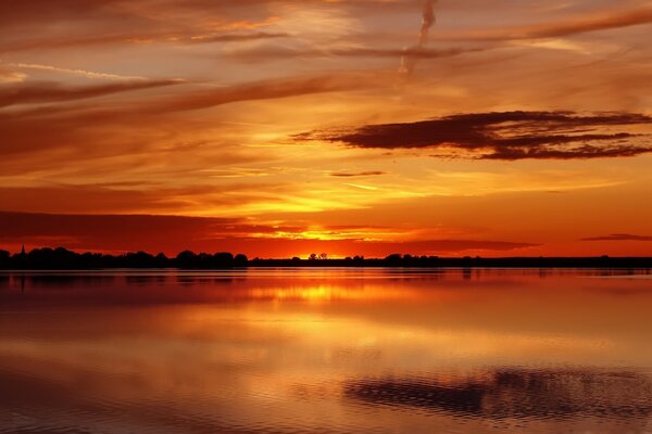 Puesta de sol en un lago Tranquilo contra el cielo