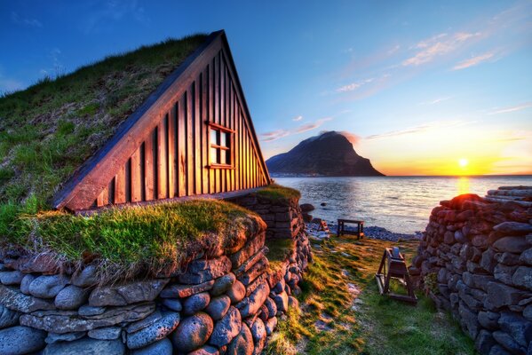 A small wooden house on the bank of the river illuminated by the sunset