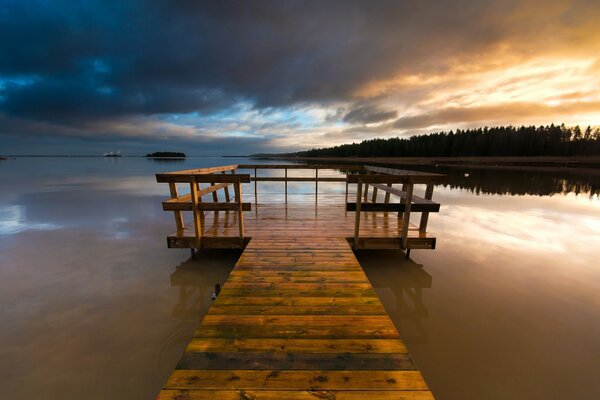 Un puente de madera conduce al puerto deportivo al lago de la noche de Suecia