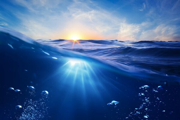 Burbujas bajo el agua y rayos de puesta de sol en el océano