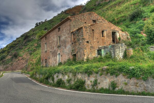 A dilapidated building in the mountains with a road