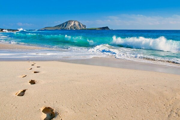 Footprints in the sand by the sea with waves