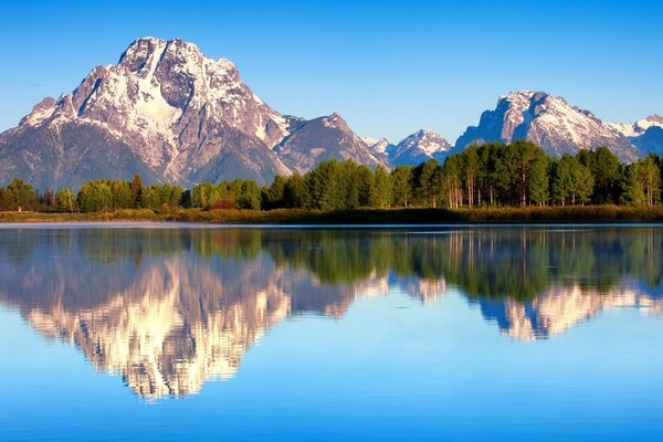Lago blu con superficie a specchio sullo sfondo delle montagne