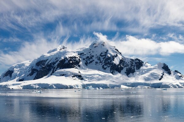 Snow-capped mountains in clouds and a lake in ice