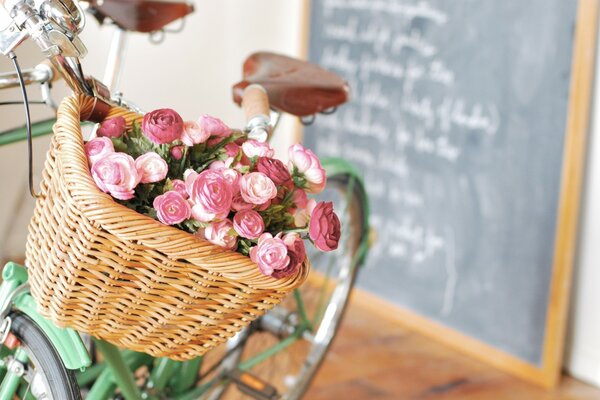 Blumen in einem Fahrradkorb auf einem Bretthintergrund