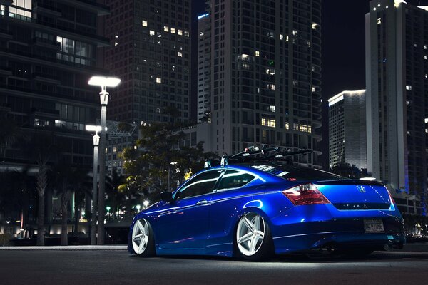 El coche azul de Honda en el fondo de la ciudad nocturna