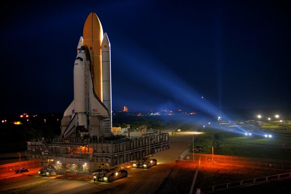 The spaceport at dusk illuminated by searchlights
