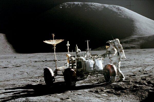 An astronaut works with equipment on the surface of the moon