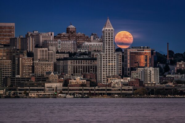 Hermosa ciudad con la Luna en el fondo