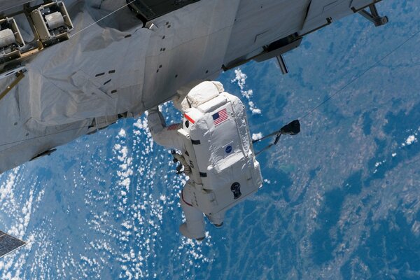 Astronauta all esterno della ISS sullo sfondo della superficie terrestre