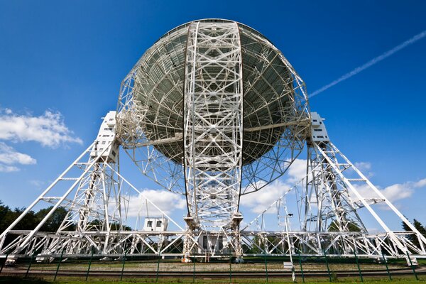 A huge radio telescope dish against a cloudy blue sky