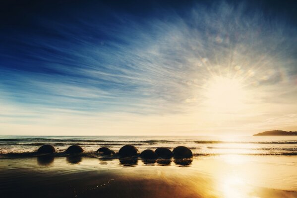Восход солнца на пляже океана новой зеландии. Камни в волнах