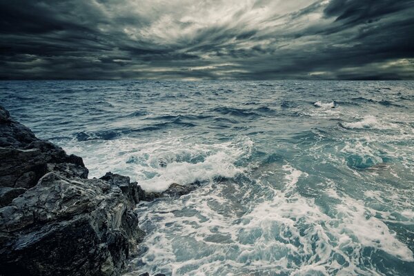 Onde che battono contro le rocce sotto il cielo coperto