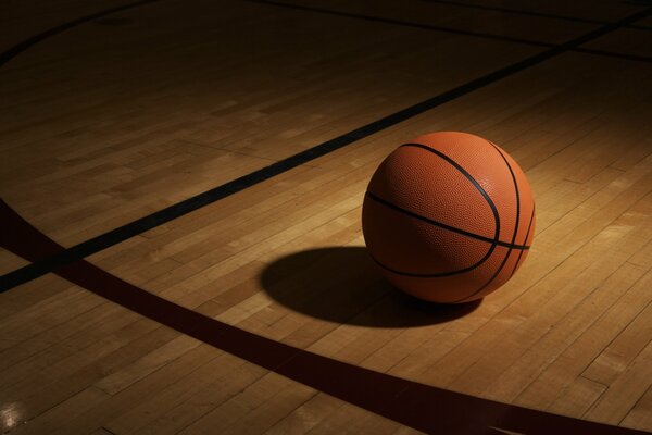 Баскетбольный мячь в тени на полу