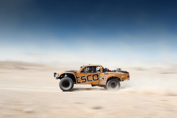 Pick-up orange dans la course dans le désert magnifiquement