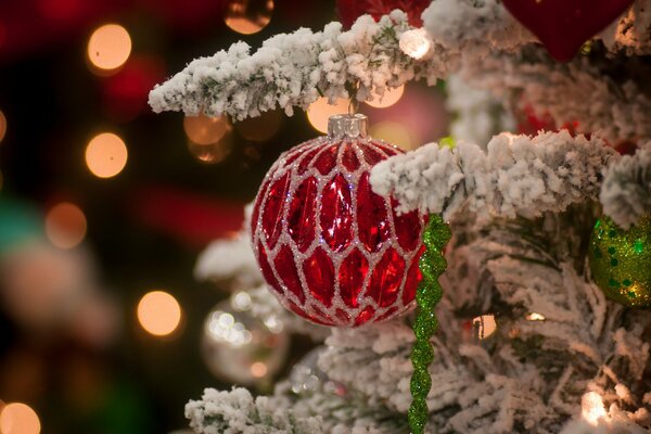 Decoración de árbol de Navidad rojo en una rama cubierta de nieve