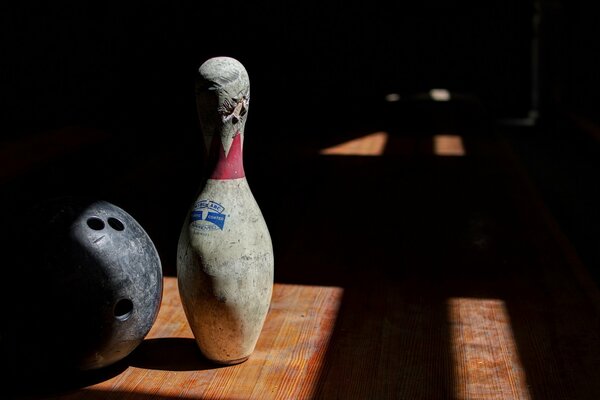 Ein dunkler Raum, das Licht aus dem Fenster beleuchtet die Kugel und den Bowling-Pin