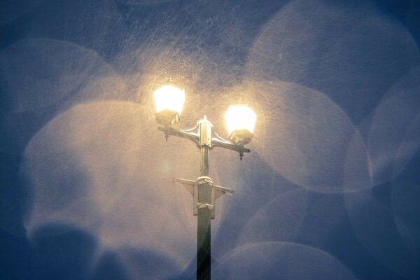 Lámpara de noche durante la nieve en el cielo oscuro