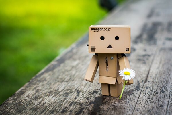 Wooden toy with a flower in hand on a blurry lawn background