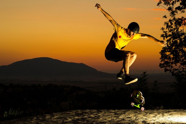 Sketboarder en t-shirt jaune et casque noir sur fond de ciel du soir