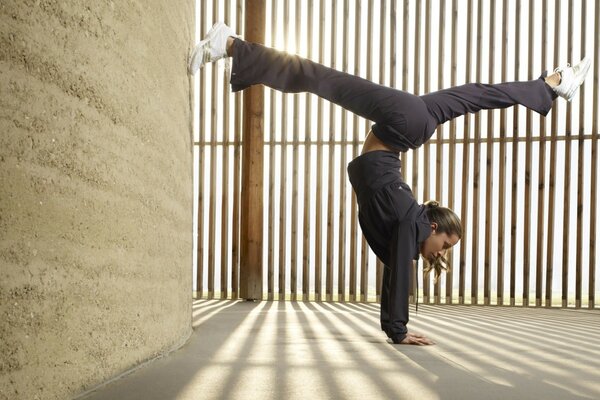 The girl is standing on her hands in the splits