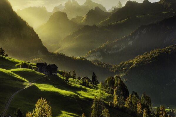 The sun illuminates houses and forests in the mountains