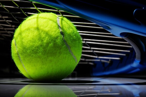 Raqueta de tenis y pelota sobre fondo negro