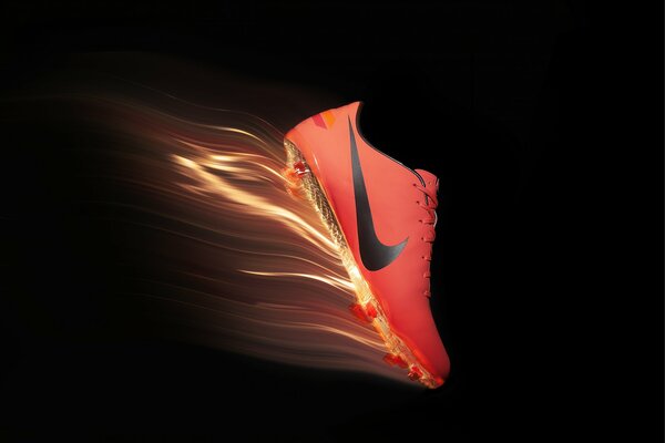 On a black background, a bright red Nike boot