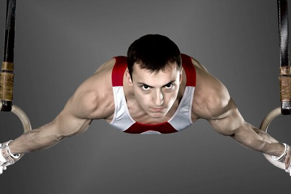 Atleta gimnasta colgando de los anillos