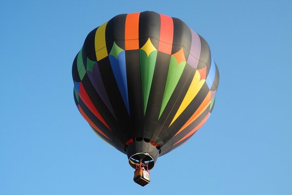 Wielokolorowy balon leci na tle błękitnego nieba