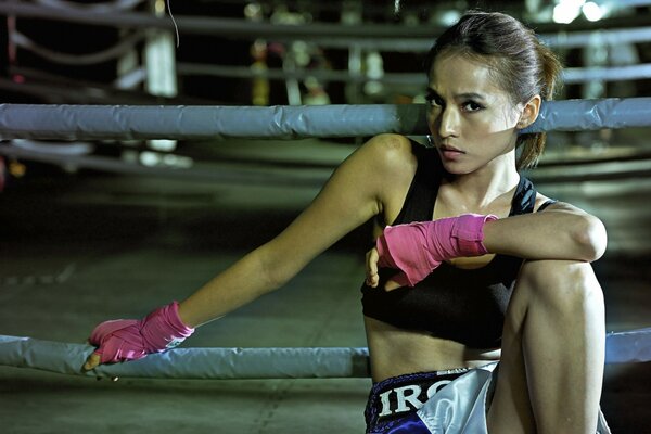 The girl athlete is sitting in pink gloves