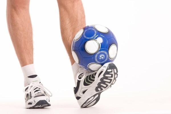 Feet in sneakers. Blue and white ball