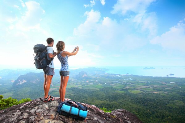 Chica con chico con mochilas viajando en las montañas