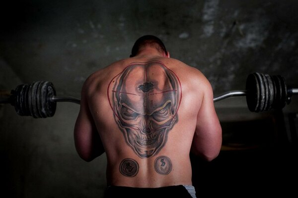 A jock with a barbell and a skull on his back